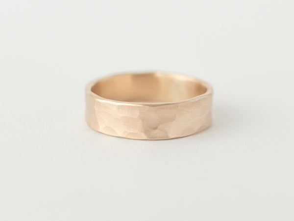 A thick textured gold band ring with a hammered finish, displayed against a white background.