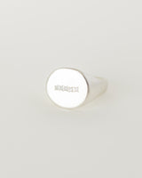A silver signet ring with five consecutive Moissanites set in a row on a white background.