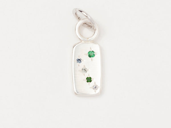 A silver charm featuring a rectangular pendant with three star-set gemstones in green, blue, and colorless hues.