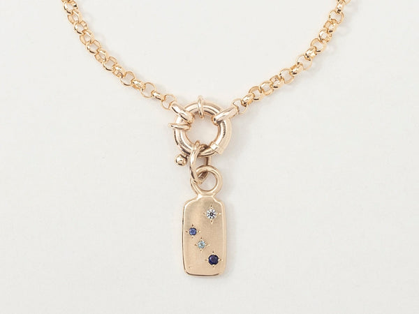 A gold bracelet with a rectangular pendant featuring a star-speckled gemstone, designed to represent a zodiac constellation.