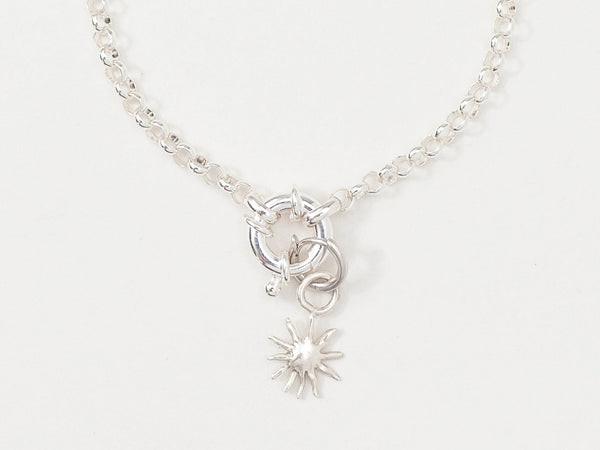 A silver bracelet featuring a small silver sun charm attached to a bold belcher chain, displayed against a white background.